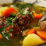 A steaming bowl of flavorful beef soup garnished with fresh herbs