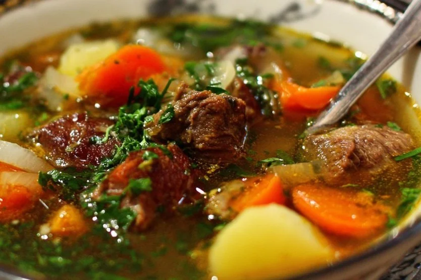 A steaming bowl of flavorful beef soup garnished with fresh herbs