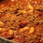Baked beans with ground beef served in a rustic bowl