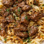 Plate of flavorful beef noodles garnished with herbs and vegetables