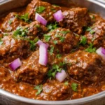A delicious bowl of beef curry served with rice and herbs.