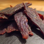 Delicious beef jerky in various flavors on a wooden table