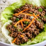 Plate of flavorful beef lettuce wraps topped with fresh vegetables