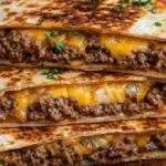 Delicious beef quesadillas with melted cheese and toppings on a plate.
