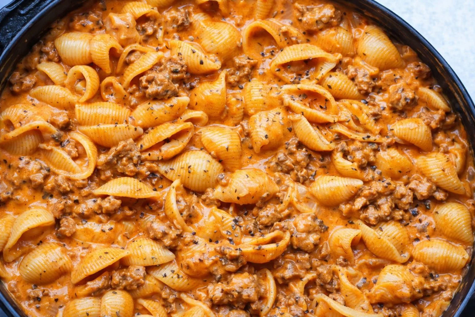 Creamy beef and shells in a bowl, garnished with parsley and served warm.