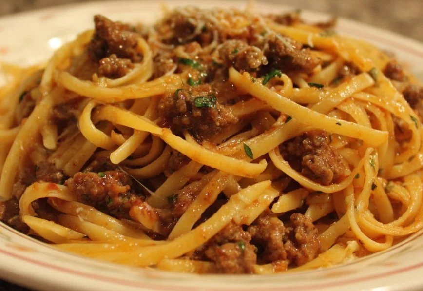 A delicious plate of ground beef pasta garnished with fresh herbs and cheese.
