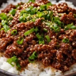 Korean ground beef and rice bowl topped with green onions and sesame seeds.