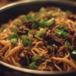 Bowl of Mongolian Ground Beef Noodles garnished with green onions and sesame seeds