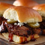 Delicious BBQ beef sandwiches served on a rustic plate with toppings.
