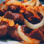 Delicious beef dish served with fresh vegetables and herbs.