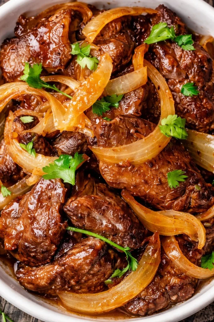 Plate of cooked beef liver garnished with herbs.