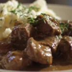 A plate of beef tips simmered in hearty gravy with fresh herbs.