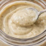 Bowl of creamy chicken soup garnished with herbs and served with bread.