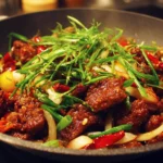 Plate of crispy beef served with vegetables and sauce, showcasing perfect texture.
