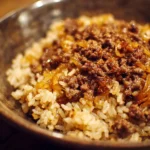 French onion ground beef and rice dish, garnished with cheese and herbs.