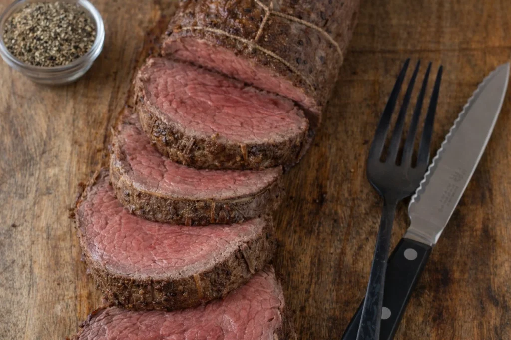 Grilled beef tenderloin on a platter garnished with herbs