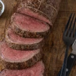 Grilled beef tenderloin on a platter garnished with herbs