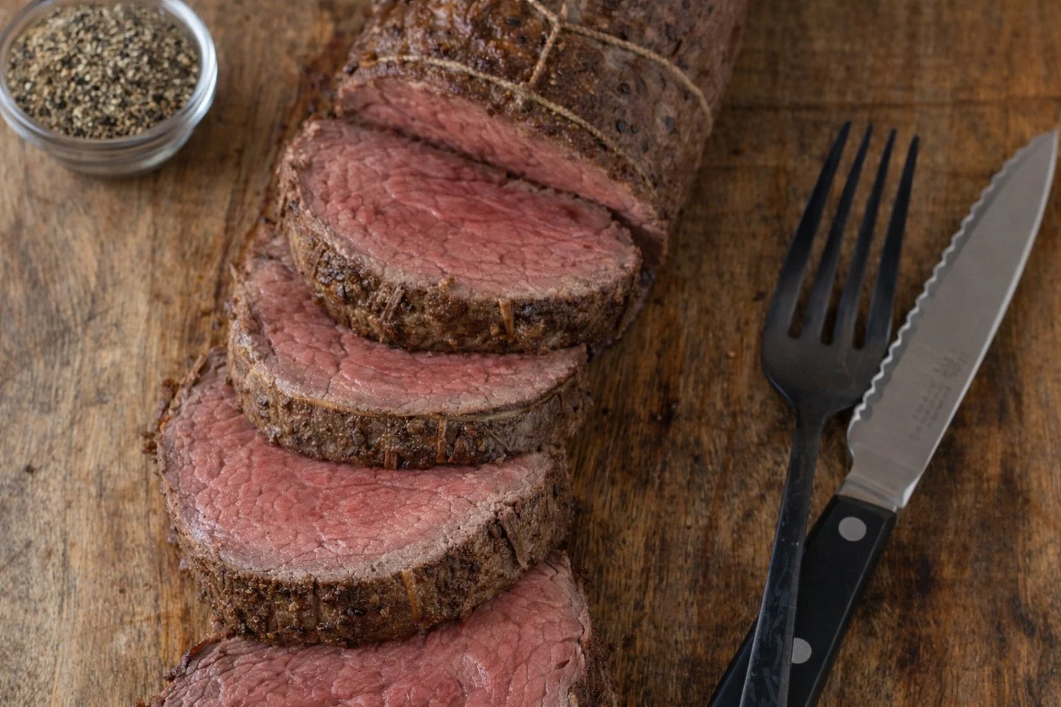 Grilled beef tenderloin on a platter garnished with herbs