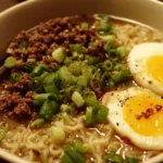 Bowl of ground beef ramen topped with green onions and sesame seeds.