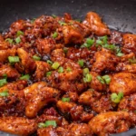 Plate of honey chicken garnished with herbs and served with rice.