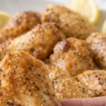 Plate of crispy Lemon Pepper Chicken Wings garnished with herbs.