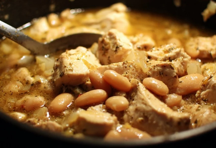 Bowl of creamy White Chili Chicken garnished with herbs