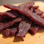 Air fryer beef jerky in a bowl with seasonings and herbs