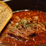 Slow-cooked beef dip sandwich served with au jus in a crock pot