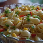 A bowl of refreshing cold pasta salad, vibrant with vegetables and dressing.