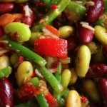 A colorful bowl of dense bean salad with various vegetables and dressing