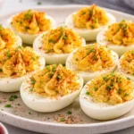 A plate of delicious deviled eggs garnished with paprika and herbs.