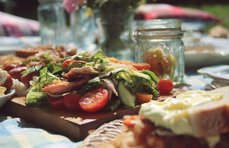 Variety of easy picnic food ideas laid out on a picnic blanket.