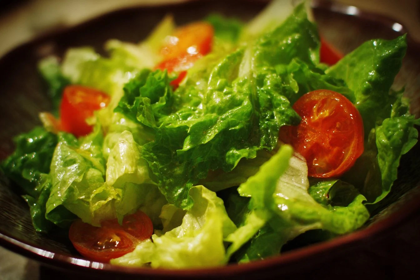 A colorful bowl of fresh green salad with vegetables and dressing