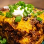 Delicious ground beef enchilada casserole topped with cheese and fresh herbs