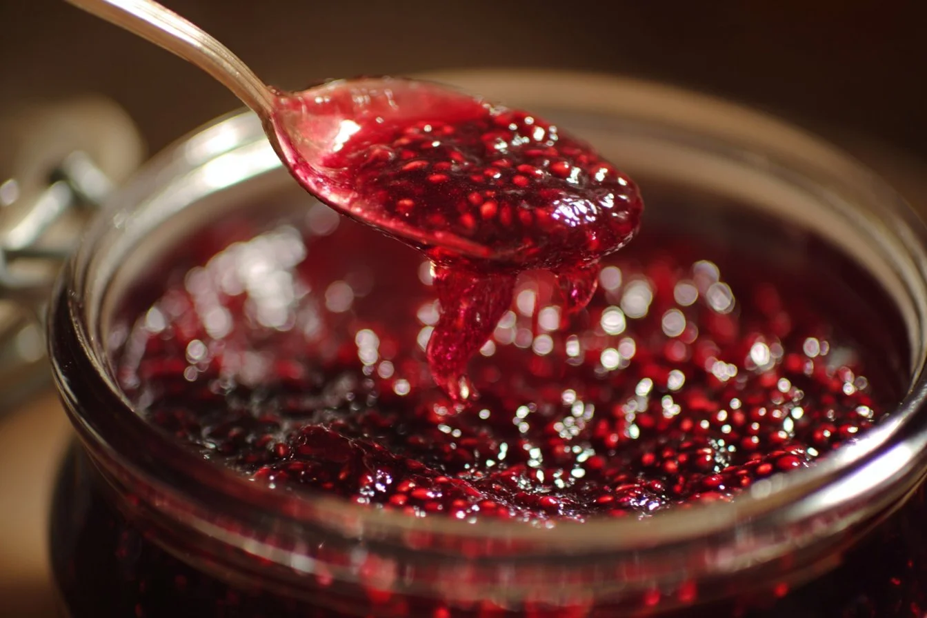 Homemade mulberry jam in a jar with fresh mulberries.