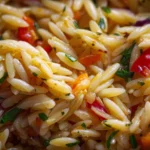 Colorful orzo pasta salad with fresh vegetables and herbs in a bowl
