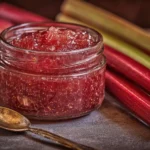 Jars of homemade rhubarb jam with fresh rhubarb stalks.