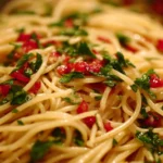 Colorful spaghetti salad with vegetables and dressing in a bowl.