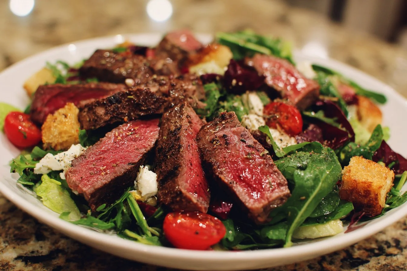 A vibrant steak salad topped with fresh greens and colorful vegetables.