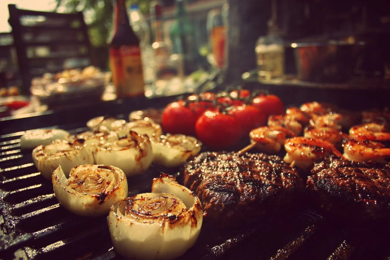 Delicious summer BBQ food displayed on a picnic table with colorful side dishes.