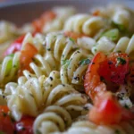 Colorful Italian pasta salad with vegetables and dressing in a bowl.