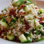 A colorful bowl of rice salad with fresh vegetables and herbs