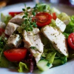 Healthy chicken salad served in a bowl with fresh vegetables and herbs.