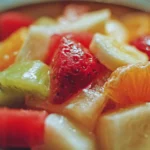 Colorful bowl of fresh fruit salad with berries, oranges, and melons
